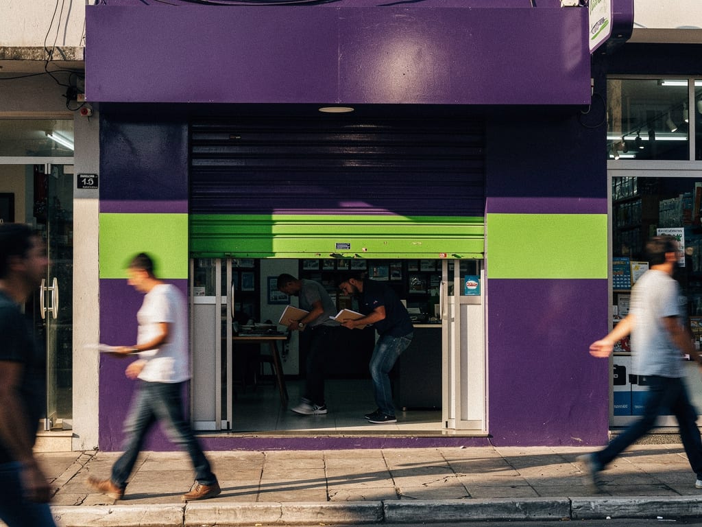 A lottery shop storefront with a violet façade and lime stripe at the end of the day